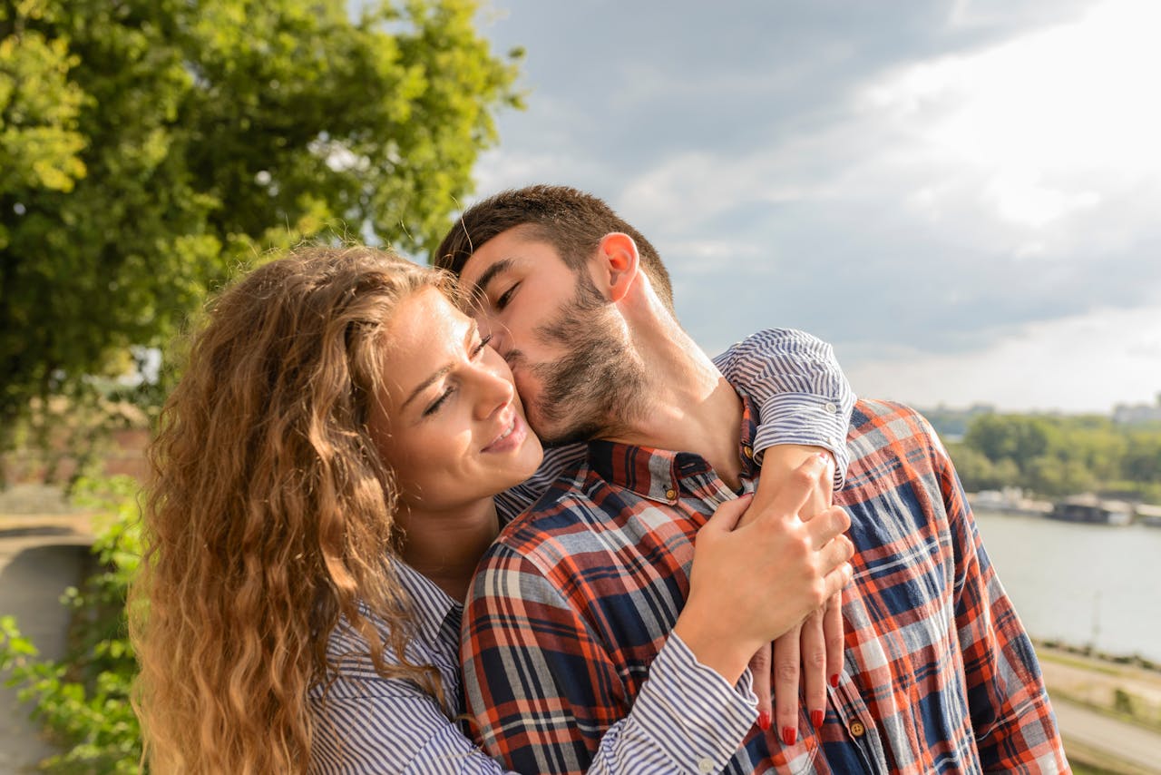 Happy couple sharing a loving embrace outdoors with a scenic background.